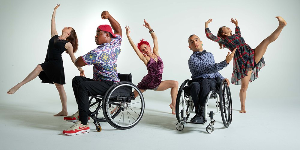 A mix of disabled and non-disabled dancers, striking different poses, wearing party dresses, dress shirts, and pants.