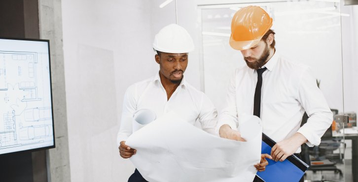 two men in hard hats in business attire discussing plans